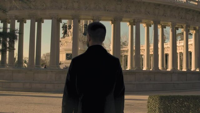MS TS Man walking by Monumento Alfonso XII / Madrid, Spain