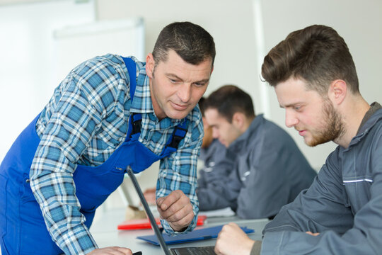 apprentices in overall using a laptop