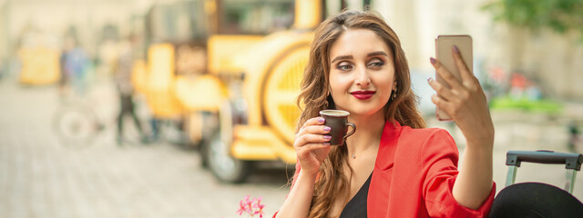 Female tourist is taking self portrait by smart phone at cafe outdoors.