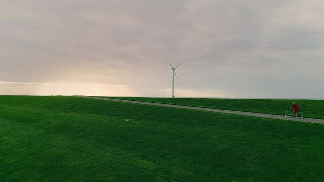 WS POV TS Girl (10-11) cycling on dyke between wind turbines / Urk, Flevoland, Netherlands