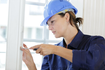 female worker unscrews fastening screws handle window