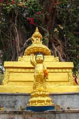 Little golden boy points his finger up, where several Buddhas are sitting in a lotus position on a huge lotus flower. Monument is located in Buddha Garden in Kathmandu city, Nepal.