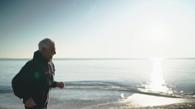 WS SLO MO TS Man jogging on beach / Rosignano, Livorno, Italy