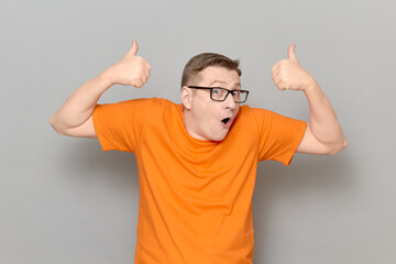Naklejka premium Portrait of amazed man raising both thumbs up in approval gestures