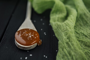 Wooden spoon with homemade salted caramel, crystals of sea salt and green gauze