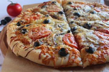 pizza with salami and olives on a wooden board