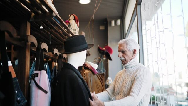 MS SELECTIVE FOCUS Man dressing mannequin in shop / Rosignano, Livorno, Italy