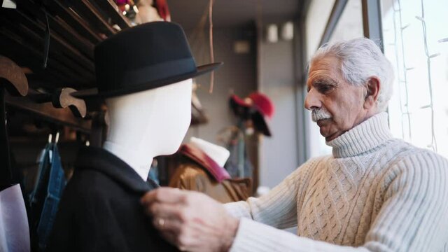 MS SELECTIVE FOCUS Man dressing mannequin in shop / Rosignano, Livorno, Italy