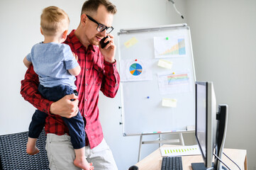 Dad must to work from home and cares of little kid. Busy father is answering the phone calls with a...