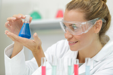 happy woman with glasses holds a blue flask