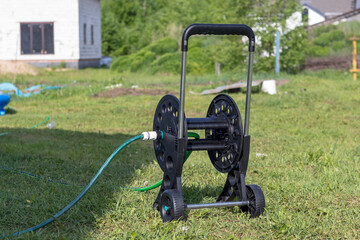 daylight. on the grass is a hose cart. close-up