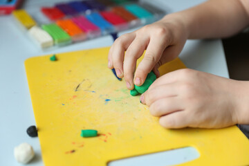 child's hands sculpt something from modelling clay