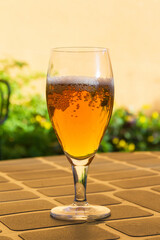 Glass with beer with foam on the table in a terrace