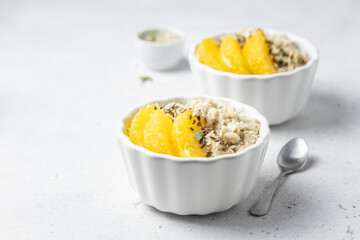 Vegan breakfast, coconut oatmeal porridge with oranges and seeds. Selective focus, copy space.