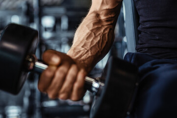 Fototapeta na wymiar Hand holding dumbbell.Close up.Muscular arm in the gym.