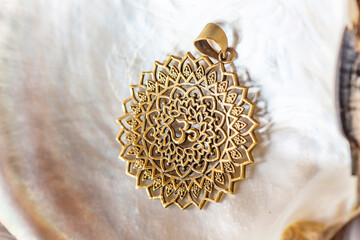 Brass pendant with om symbol in lotus round shape mandala on white shell background