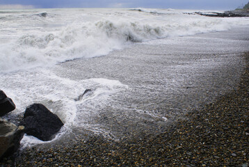 Storm, strong waves, sea coast, pebbles on the beach
