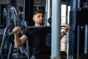 Fototapeta na wymiar Fit man exercising at the gym on a machine.