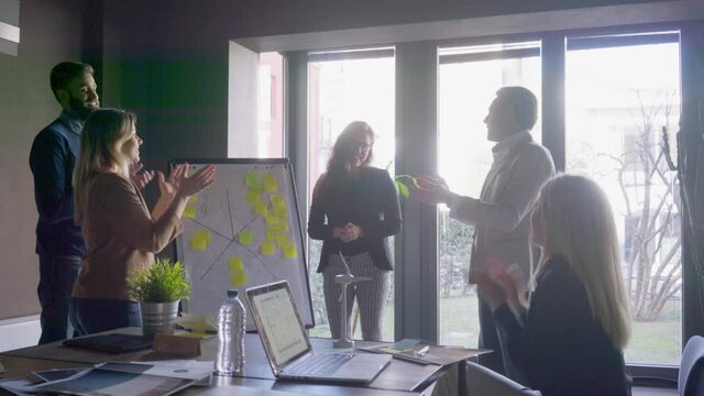WS Business people applauding colleague in office / Milan, Italy