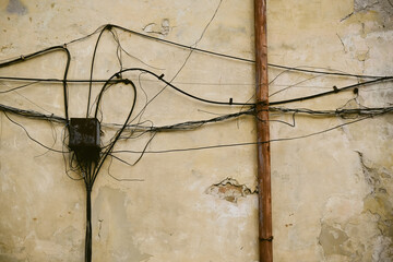 Electrical wires on old brick wall. Electricity cables hanging from brick wall
