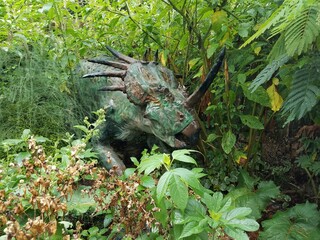 green dinosaur with horns in the forest