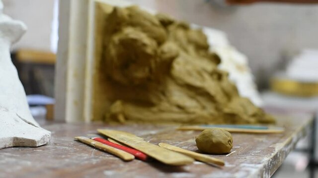 Sculptor create clay model of a Corinthian capitel with scrolls and unfurled acanthus leaves in restoration workshop
