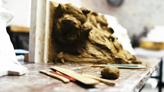 Sculptor create clay model of a Corinthian capitel with scrolls and unfurled acanthus leaves in restoration workshop