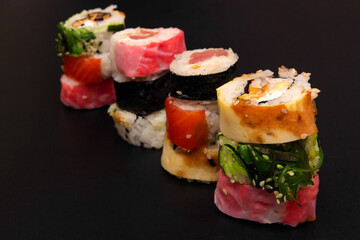 Pile of multiple hosomaki sushi on black background