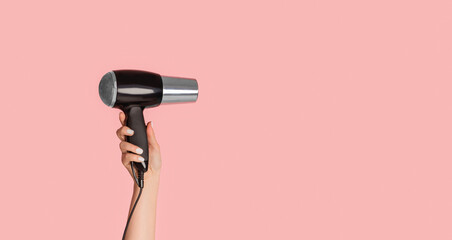 Closeup view of female hand showing modern hairdryer on pink background, empty space