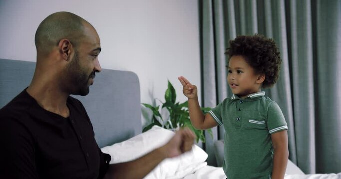 MS SLO MO Father and son (2-3) playing rock paper scissors on bed / Claremont, Cape Town, South Africa