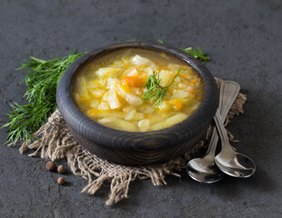 Vegan vegetable soup of cabbage, potatoes, carrots with dill on a wooden bowl in rustic style