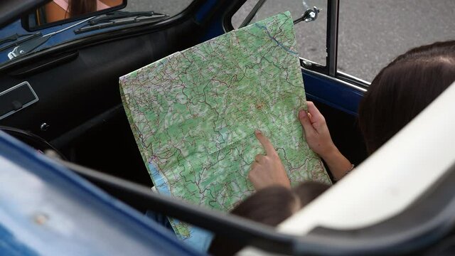 MS HA Friends sitting in car and looking at map / Florence, Italy