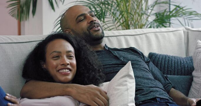 MS Couple reclining on sofa in living room and watching TV / Claremont, Cape Town, South Africa