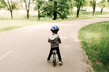 Fototapeta premium Happy little boy riding a bike running in the Park