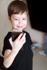 boy with a mobile phone speaks by video calling at home.  the scoolboy  communicates via video link. Video chatting at home. Modern technology and children