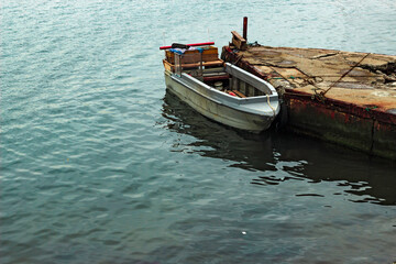Fototapeta na wymiar Fishing boat moored to the old pier.
