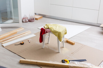 Wooden shelves laying on round table and senior man crafting furniture at apartment balcony. House improving