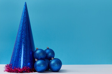 Festive balls for decoration. Cap with red tinsel. Christmas and new year concept. Copy space for text. Blue background