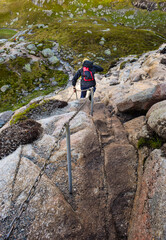 Chains on the way to famous Kjeragbolten help tourists climb steep cliffs. Norway.