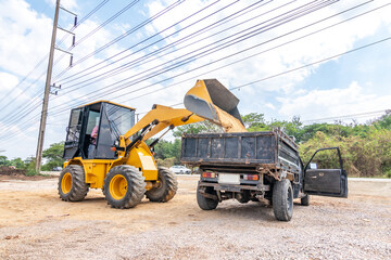 Heavy yellow Bulldozers are loading sand at the truck. Wheel loader machine unloading sand.