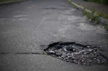 Broken asphalt and cracks on the road surface