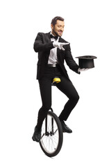 Magician riding a unicycle and performing a magic trick with a hat © Ljupco Smokovski