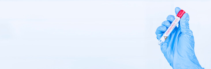 Hand holds a test tube containing a blood sample, test tube with blood for Covid-19 (coronavirus) analyzing