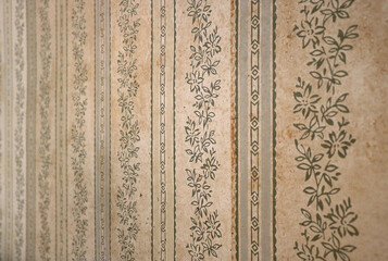 vintage decorative wall paper surface with a floral pattern from aged texture of an old house interior - retro background wallpaper