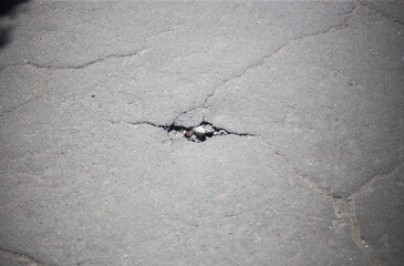 Broken asphalt and cracks on the road surface
