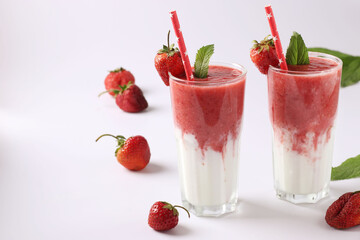 Two servings of homemade smoothies with fresh strawberries, mint and yogurt in glasses on white background, Diet and weight loss control concept