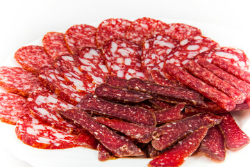 Sliced smoked sausages on a white plate, close up.