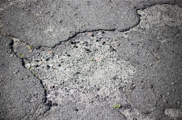 Broken asphalt and cracks on the road surface