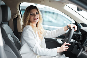 Young woman driving a car. Elegant business lady driving an expensive car