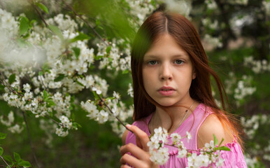Obraz premium a girl in protective face mask stands near blossoming cherry tree during quarantine due to the coronavirus pandemic